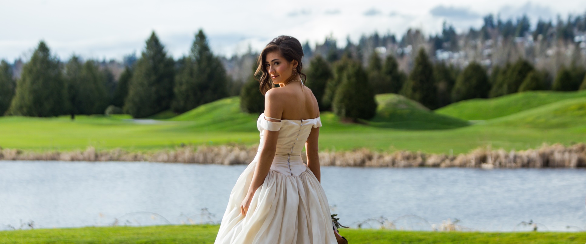 Bride posing for wedding photos overlooking the lake at the Golf Course