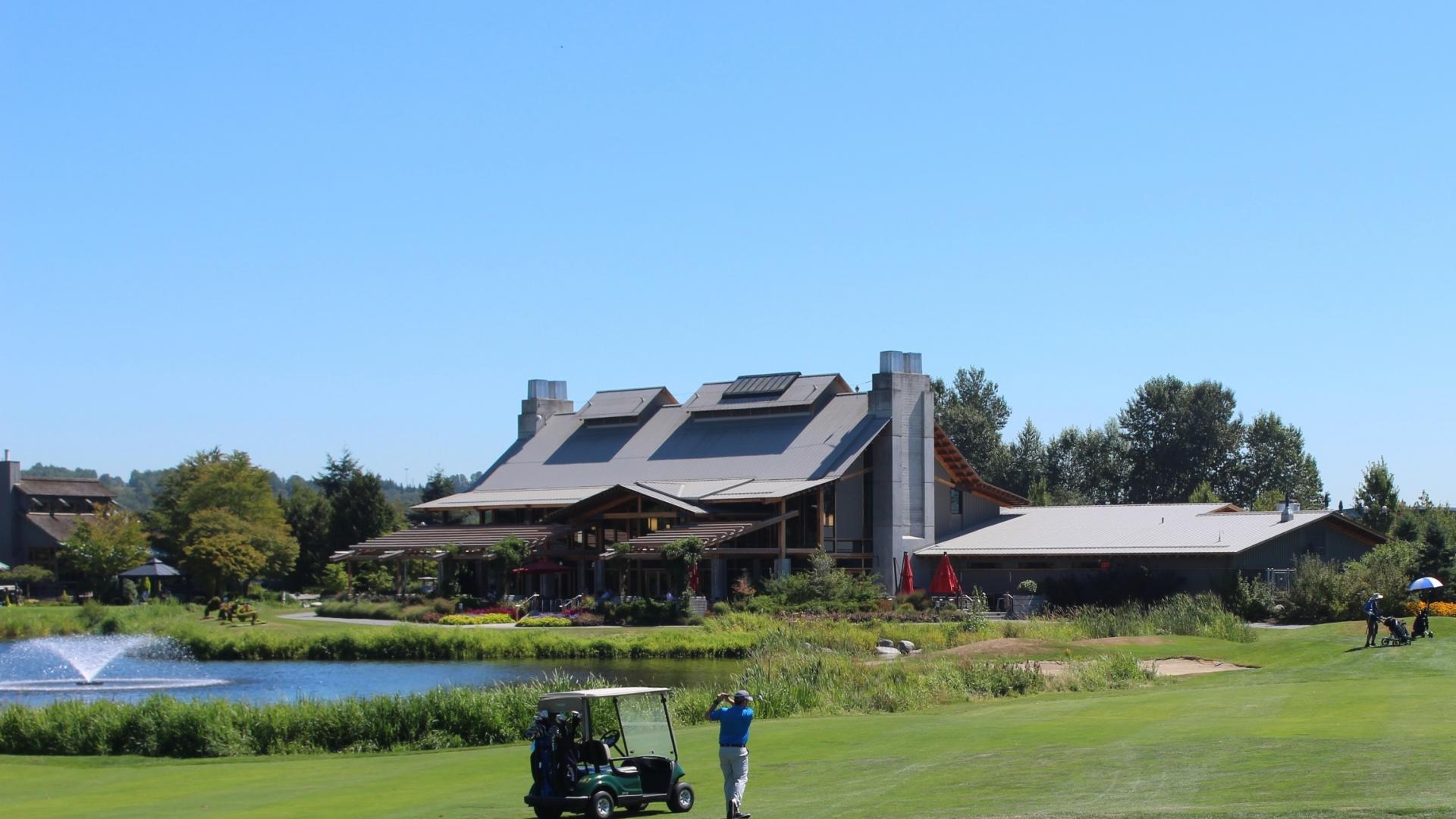 Riverway Clubhouse serves as the backdrop for a golfer taking a swing