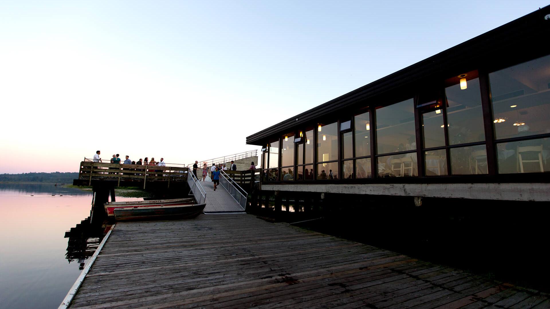 People standing on a dock at sunset.